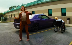 Emma Stone dances next to a person in a wheelchair and a purple Dodge car.